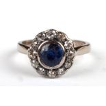 An 18ct white gold sapphire and diamond ring, the central sapphire within a halo of twelve diamonds,