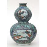 A Chinese double gourd vase decorated with landscape scenes within panels, blue seal mark to the