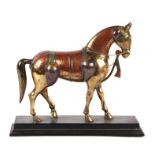 A Kashmiri style cast brass horse mounted on a wooden plinth, 28cms wide.