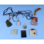 A quantity of Chinese jade like and stone pendants.