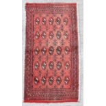 A small Persian Turkoman rug with repeated guls on a red ground, 128 by 58cms.