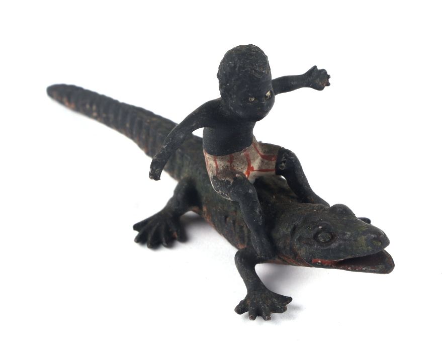 An antique novelty Vienna cold painted bronze miniature depicting a black boy ridding a crocodile,