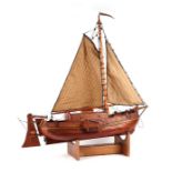 A scratch built model of a single masted boat, on stand, 77cms long.