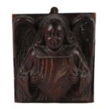 A carved oak plaque depicting a winged angel holding a shield, 18 by 18cms.