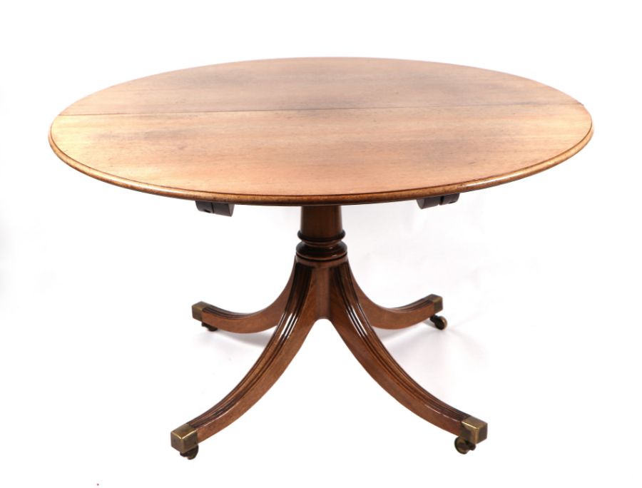 A George III style mahogany circular tripod dining table inset with one extra leaf, on a turned