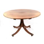 A George III style mahogany circular tripod dining table inset with one extra leaf, on a turned