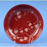 A Chinese shallow bowl decorated with prunus on a red ground, red seal mark to the underside,