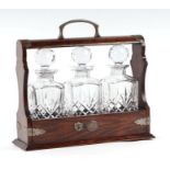 An oak three-bottle tantalus with silver plated mounts.Condition ReportOne stopper is broken where