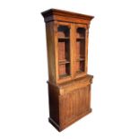 A Victorian mahogany bookcase on cupboard, the pair of glazed doors enclosing a shelved interior