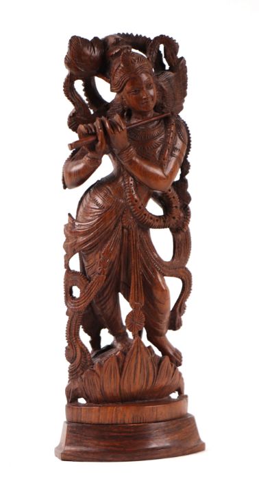 A large Indian hardwood figure depicting Krishna playing a flute, 34cms high.