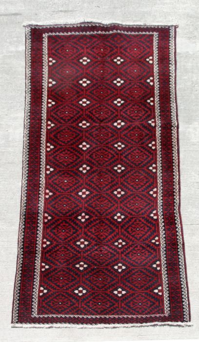 A fine quality Persian Baluch woollen hand knotted runner with repeat gul medallions on a claret