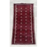 A fine quality Persian Baluch woollen hand knotted runner with repeat gul medallions on a claret