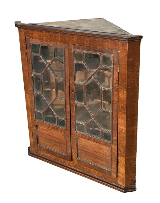 A 19th century mahogany hanging corner cabinet, the pair of astragal glazed doors enclosing a