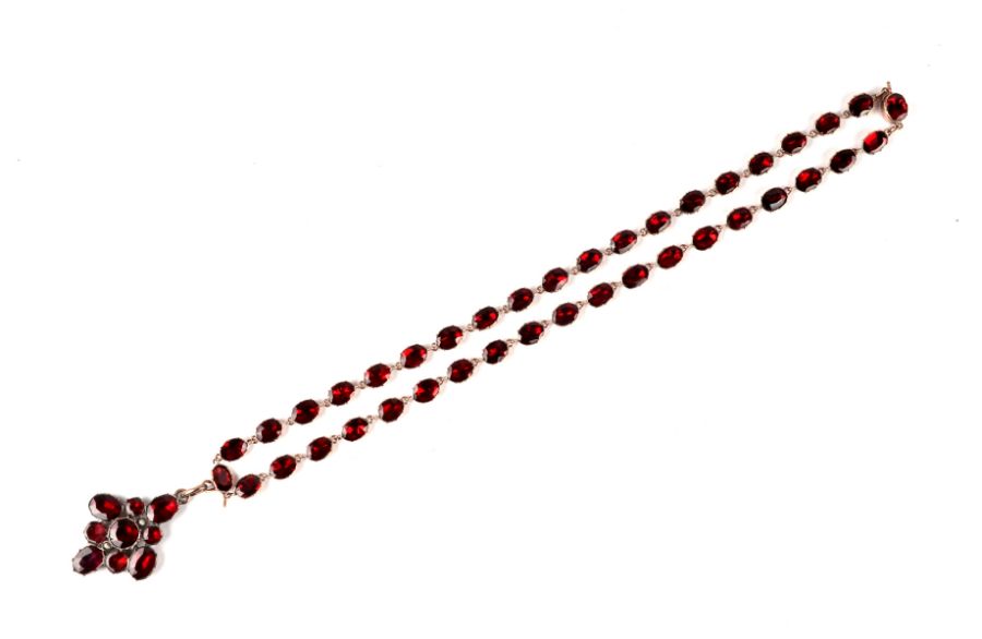 An early 19th century yellow metal mounted garnet riviere pendant drop necklace.