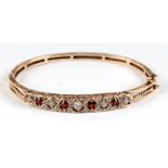 A 9ct gold hinged bangle set with white and red stones, 15.6g.