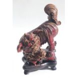 A Chinese Shiwan oxblood pottery figure depicting a temple lion and cub, mounted on a hardwood