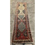 A Persian hand knotted runner with repeating geometric motifs on a multi coloured ground within a