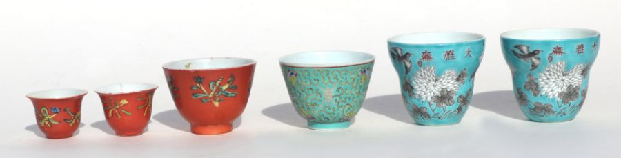 A pair of Chinese tea cups decorated with flowers, birds and calligraphy, on a turquoise ground,