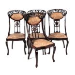 A set of four Art Nouveau mahogany dining chairs with carved and upholstered back rails, pierced