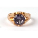 A yellow metal mounted dress ring set with a large amethyst coloured stone, approx UK size 'N', 5.