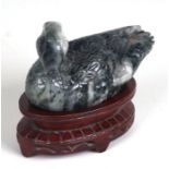 A Chinese carved hardstone figure of a duck, 15cms wide, on a hardwood stand with pierced