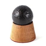 A roundshot iron cannon ball. Approximate diameter of 6.5cms (2.5ins) on a turned oak mount