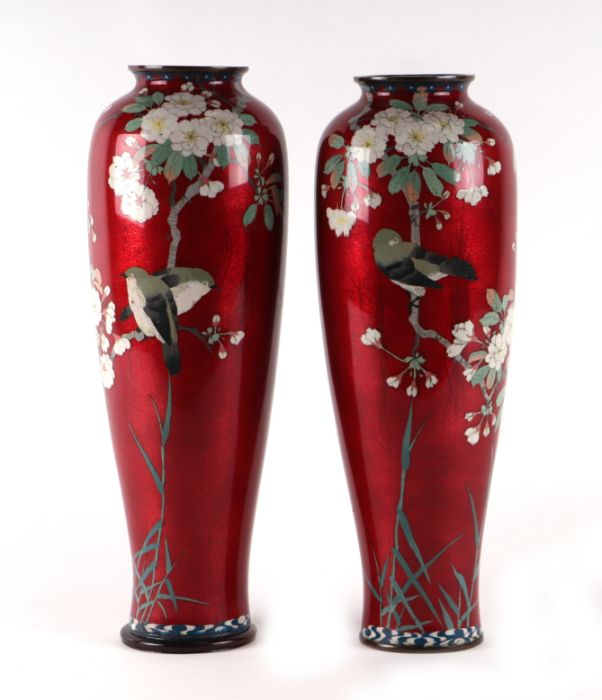 A pair of large Japanese cloisonne vases decorated with birds and flowers, on a red ground, 38cms