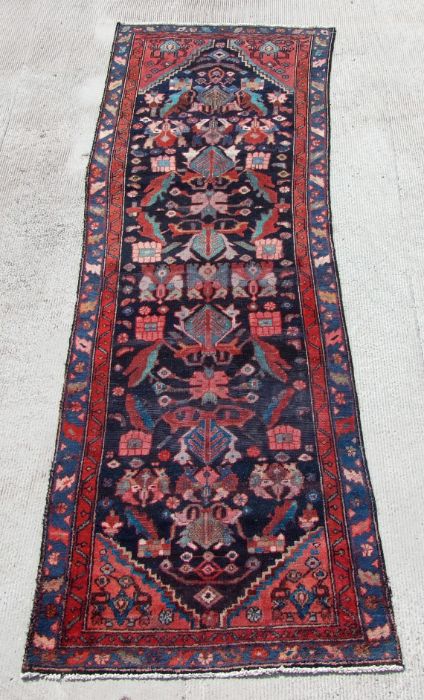 A Persian runner with repeated floral decoration within multi borders, on a blue ground, 290 by