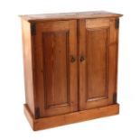 A pine cabinet with a pair of panelled doors enclosing a fitted interior, on a plinth base, 90cms