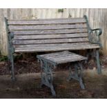 A slatted wooden garden bench with cast iron ends, 148cms wide; together with a matching table,