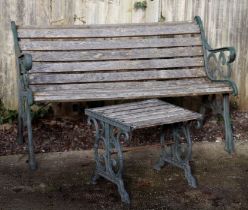 A slatted wooden garden bench with cast iron ends, 148cms wide; together with a matching table,
