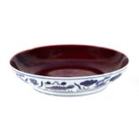 A Chinese shallow footed bowl with internal sang de boeuf glaze and external blue & white fish and