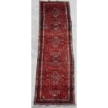 A Persian Hamadan runner with floral decoration within floral borders, on a red ground, 420 by
