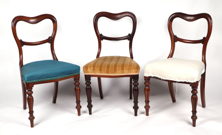 A set of three Victorian walnut balloon back dining chairs with overstuffed seats and turned front