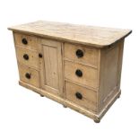 A late Victorian pine dresser base with central cupboard flanked by two rows of three drawers, on