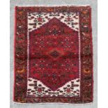 A Persian Hamadan hand knotted woollen rug with stylised design within borders, on a red ground, 140