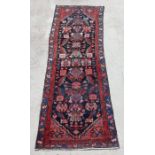 A Persian runner with repeated floral decoration within multi borders, on a blue ground, 290 by