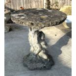 A reconstituted stone bird table with circular top, on a cast cherub form support, 50cms dimeter.