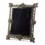 A large Victorian brass strut mirror, the pierced frame with cherub masks, overall 37 by 46cms.