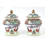 A pair of Chinese famille rose lidded jars decorated with chickens, six character red mark to the