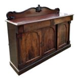 A Victorian mahogany sideboard with two frieze drawers above three arched panelled doors enclosing a