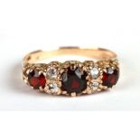 A 9ct gold ring set with three garnets and four diamonds, approx UK size 'Q', 2.3g.