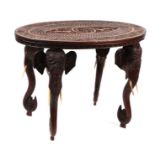 An Indian hardwood occasional table, the oval top with profusely carved decoration, on elephant head