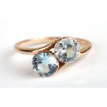 A 9ct gold two-stone crossover ring set with pale blue stones, approx UK size 'K', 2.2g.