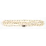 A graduated pearl necklace with yellow metal diamond set clasp, the central diamond on the clasp