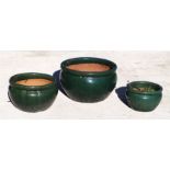 A set of three green glazed terracotta pots, the largest 45cms diameter (3).