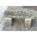 A reconstituted stone bench, the rectangular top on cast supports with rose decoration, 92cms wide.