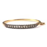 A 19th century yellow metal diamond set hinged bangle set with sixteen graduated diamonds, the