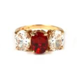 A 14ct gold three-stone dress ring with a large oval red stone flanked by two white stones, approx