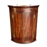 A George III mahogany bowfront corner cupboard with inlaid boxwood stringing, 74cms wide.